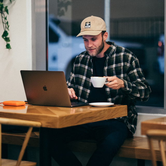 Man sitting at coffee shop looking at laptop