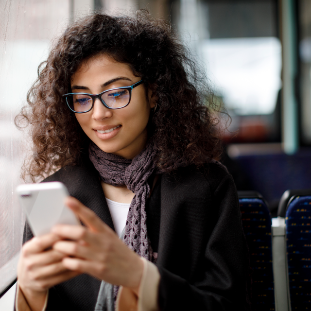 Woman riding public transportation and looking at a smartphone