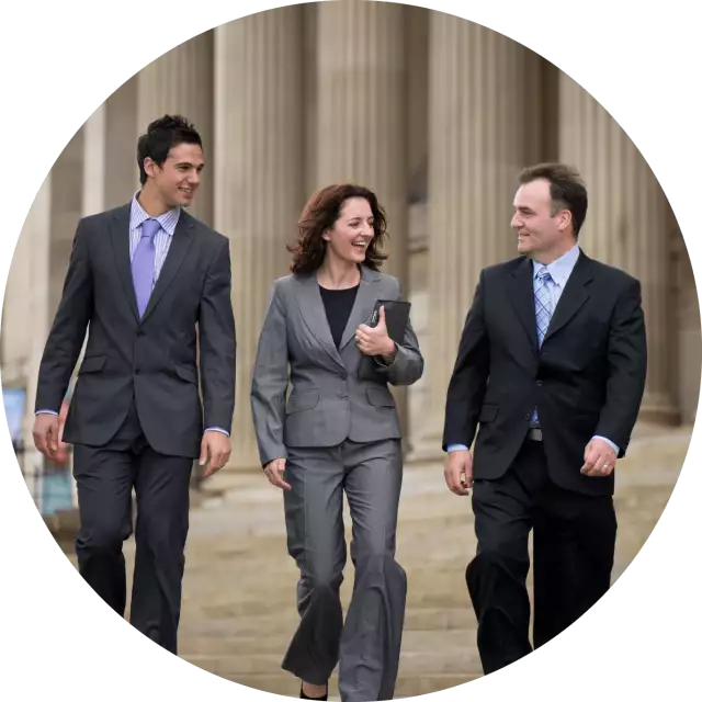 Two men and one woman in suites walking in front of government building
