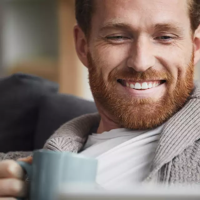 Man holding a cup of coffee and smiling