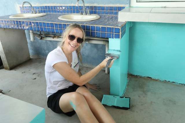 A Conga team member helps paint a bathroom