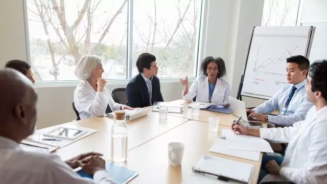 Scientists in lab coats holding a forecasting meeting