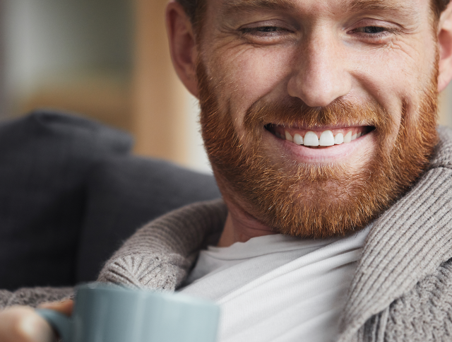Man holding a cup of coffee and smiling