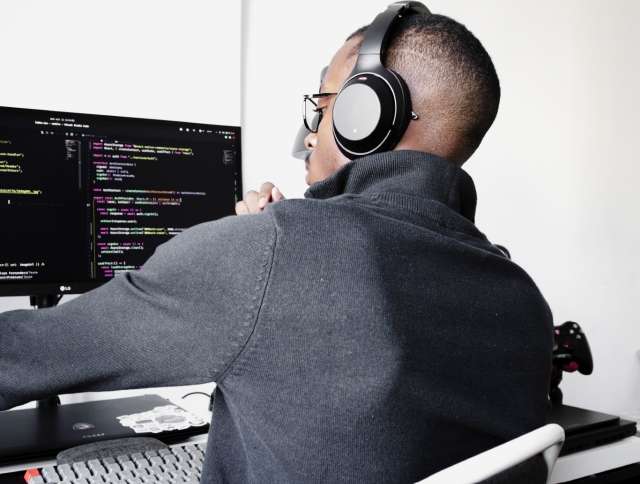 Man wearing headset looking at code on computer