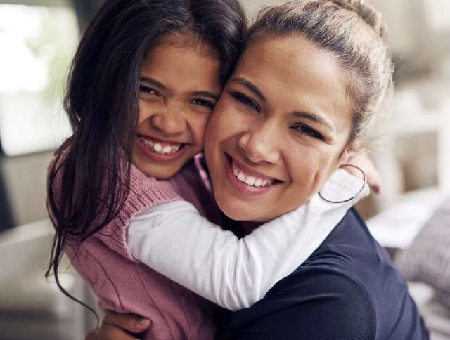 Mom hugging daughter and smiling
