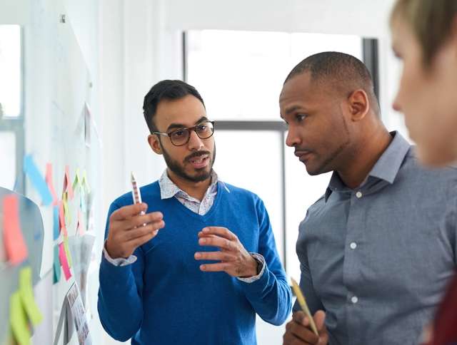 Coworkers using sticky notes on wall