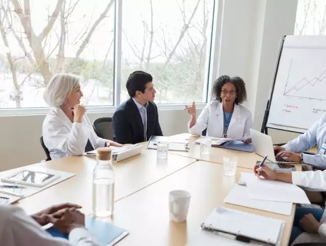 Scientists in lab coats holding a forecasting meeting