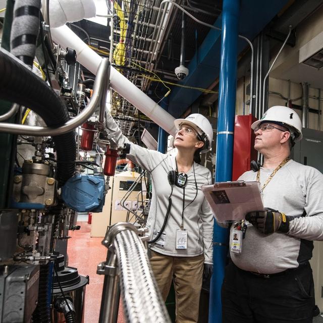 Man and woman in hardhats working on machinery