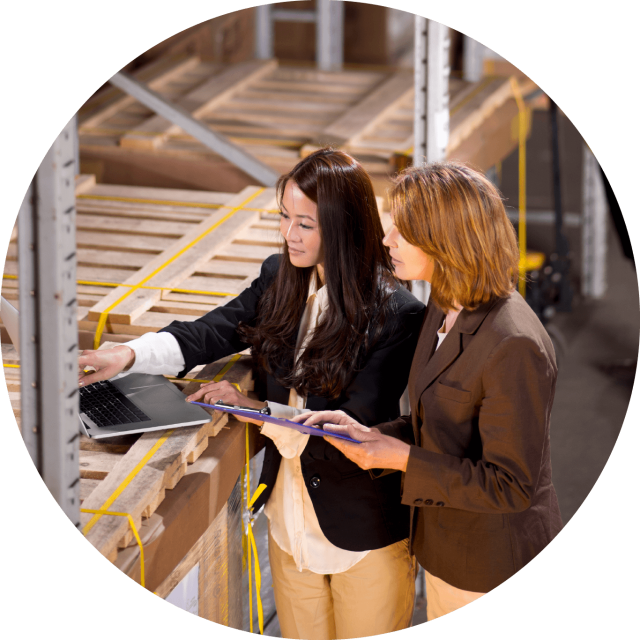 Two woman looking at a laptop in a warehouse