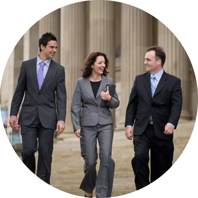 Two men and one woman in suites walking in front of government building