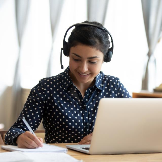 Woman on headset writing in notebook