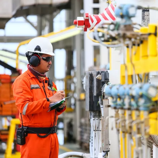 Man taking notes looking at machinery