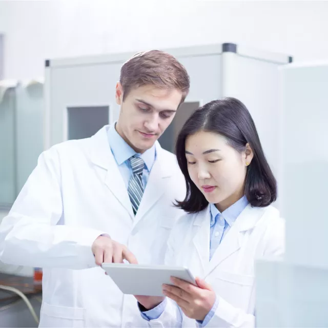 Scientists in lab coats looking at tablet