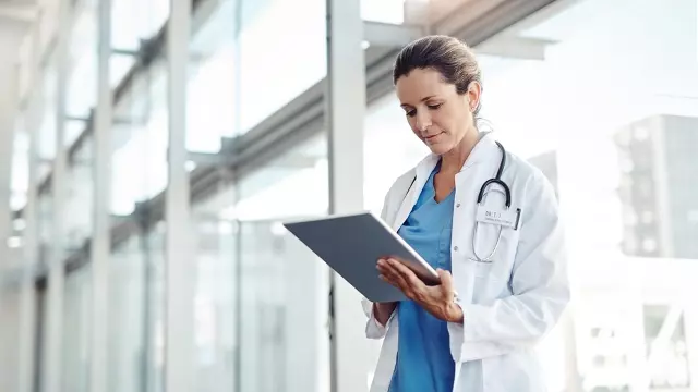 Doctor looking at ipad to review Medtech renewal contracts
