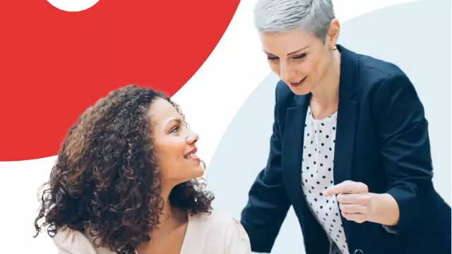 Two woman smiling while looking at a laptop