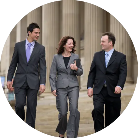 Two men and one woman in suites walking in front of government building