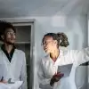 Healthcare team in lab coats examining medical scans on a wall in a clinical setting.